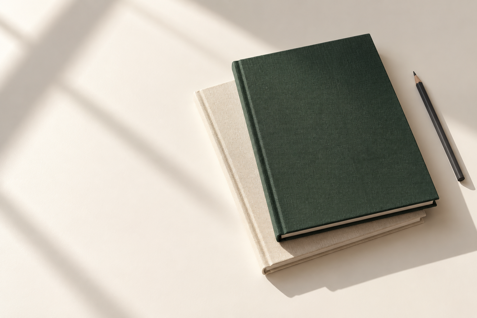 Packaging concept: closed green and ivory workbooks beside a pencil